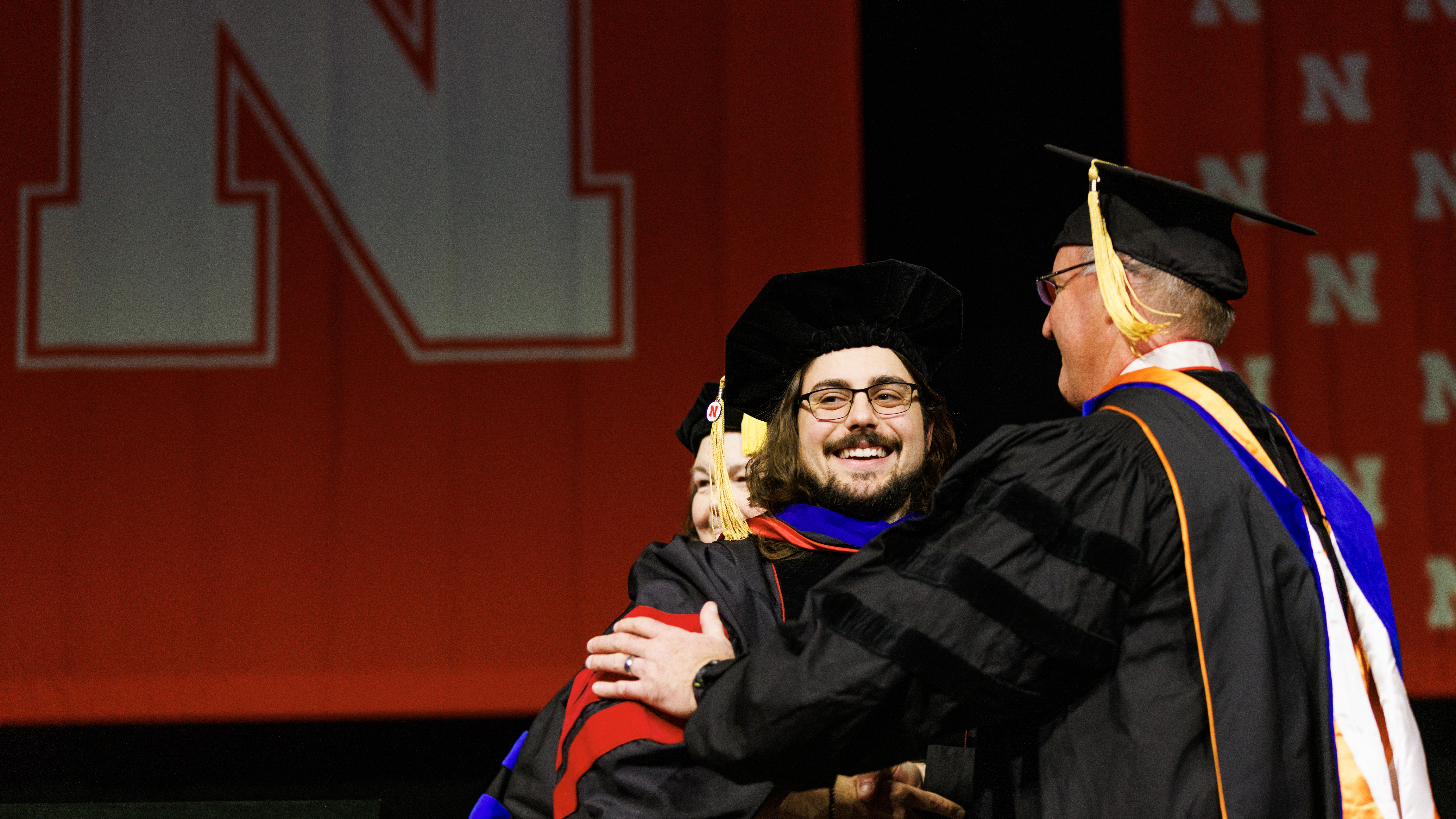 Nate Korth smiles to family and friends as he is congratulated by adviser Andy Benson on his doctoral degree. 