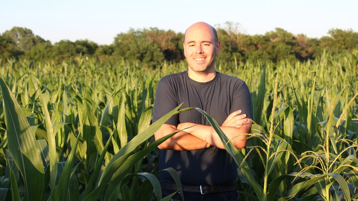 Dr. James Schnable standing in a field of corn with his arms crossed. He is smiling. 