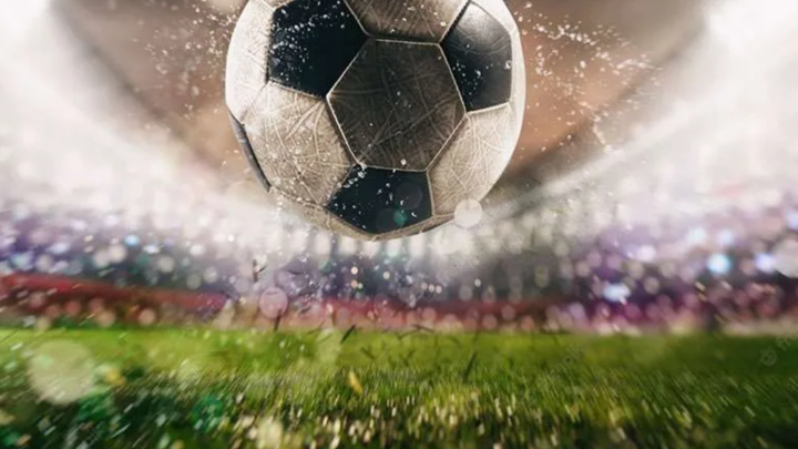 Soccer ball flying through the air above a turf field. 
